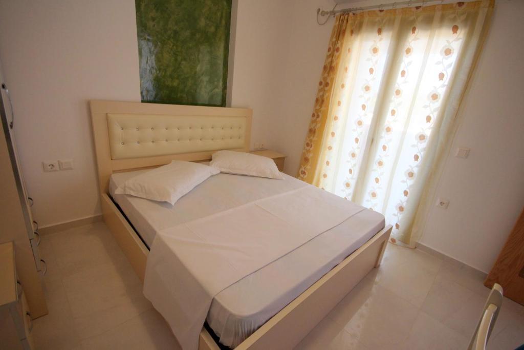 a bedroom with a white bed with a window at Mihal Suites in Sarandë