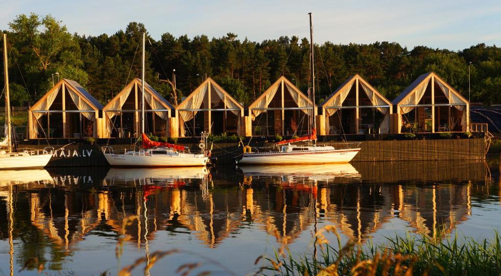 a group of boats are docked in the water at Peldmaja in Pāvilosta