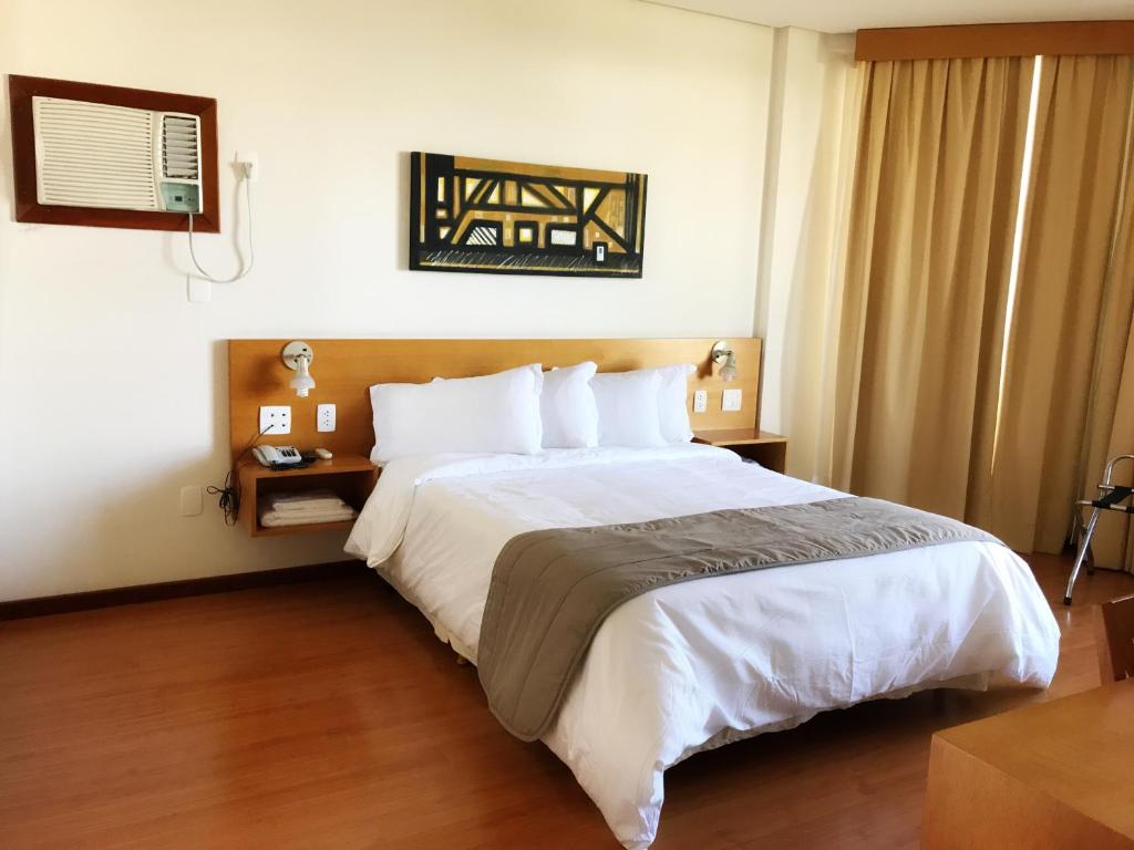 a bedroom with a large bed in a hotel room at Serema Palace Hotel in Lavras