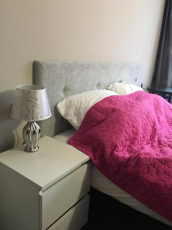 オクニンカにあるPrywatne pokoje hotelowe Okuninkaのベッド(ピンクの掛け布団付)、ナイトスタンド(ランプ付)