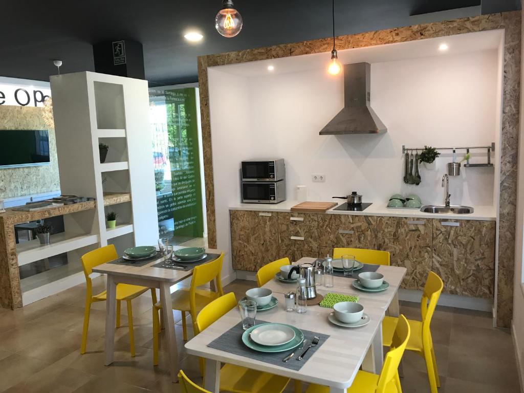 a dining room with a table and yellow chairs at Albergue O Pedrón in Padrón