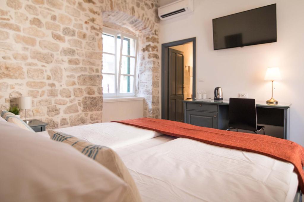 um quarto com uma cama, uma secretária e uma televisão em Mediterraneo Luxury Rooms em Sibenik