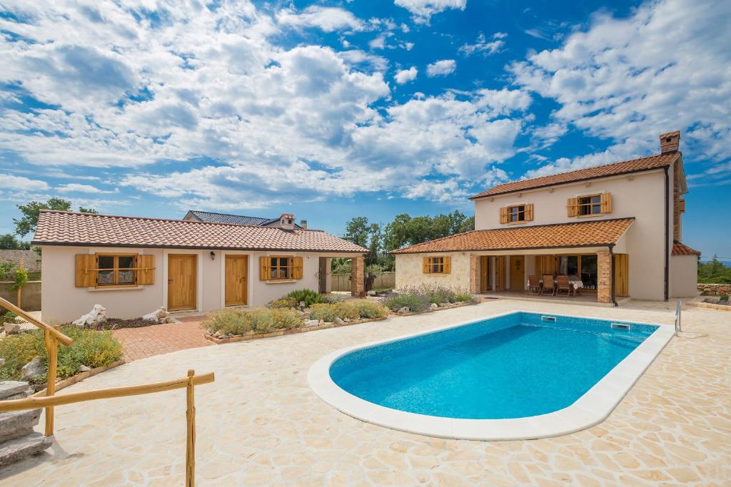 a house with a swimming pool in front of a house at Holiday house Hojevica - Kras, Krk in Kras