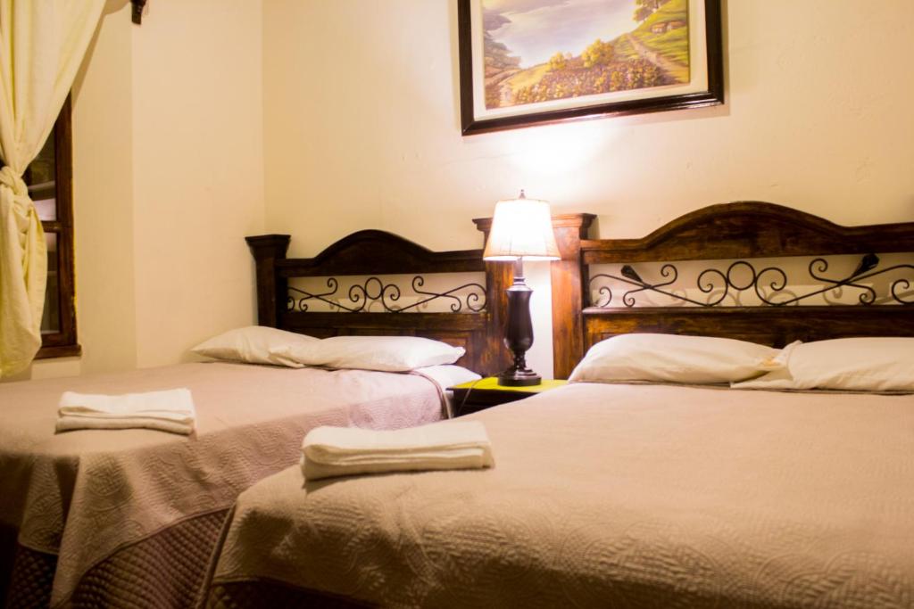 two beds in a room with a lamp on a table at Dionisio Inn in Antigua Guatemala