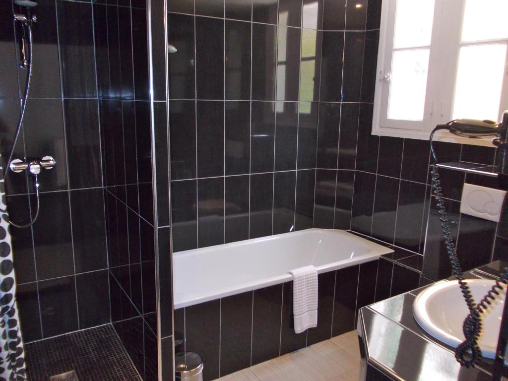 a black tiled bathroom with a tub and a sink at Hotel Molière in Cannes