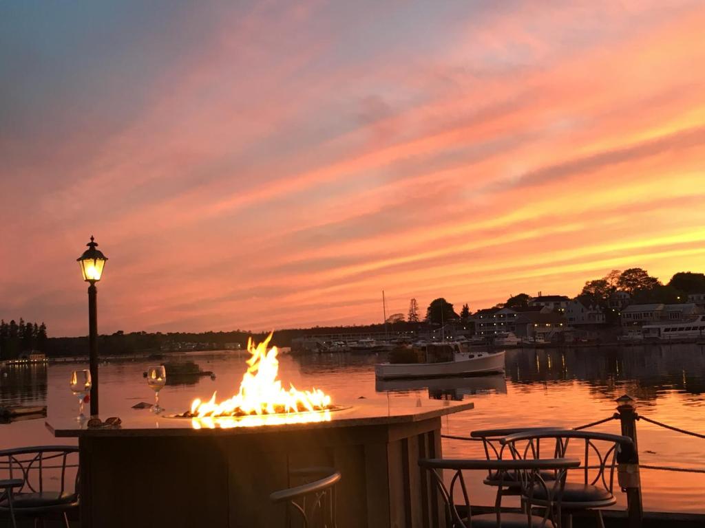 a sunset scene with a lighthouse and a boat on the water at Boothbay Harbor Inn in Boothbay Harbor