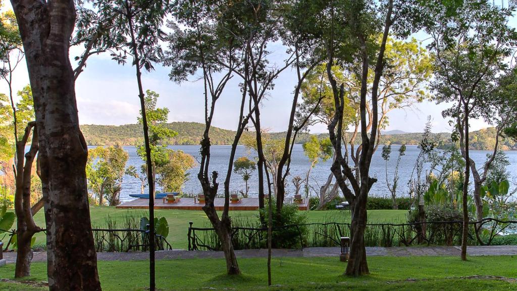 a view of the water from a park with trees at The Deer Park Hotel in Giritale
