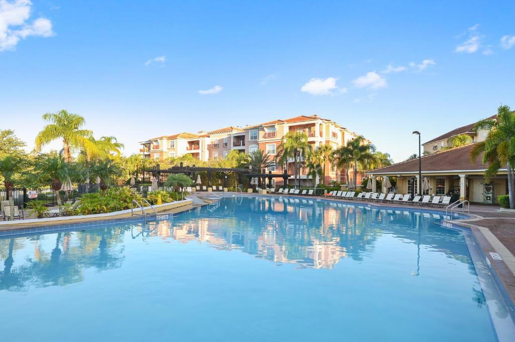 a large swimming pool with palm trees and buildings at Orlando Resort Rentals at Universal Boulevard in Orlando