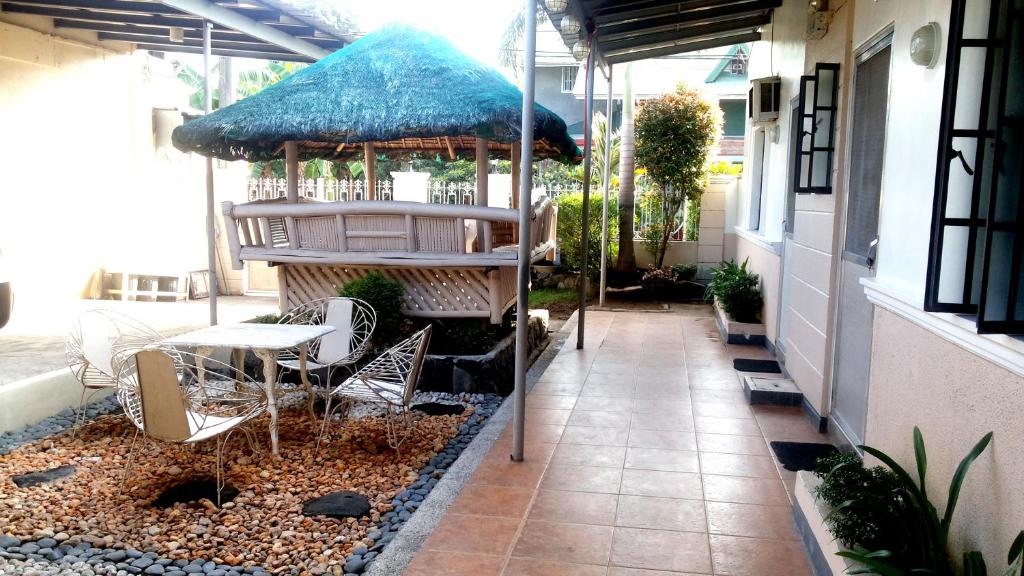 Balanga的住宿－BTH Traveller's Home，庭院配有桌椅和遮阳伞。