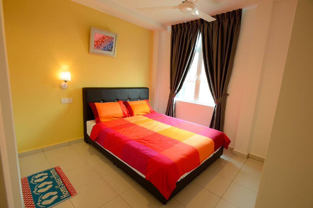 sypialnia z łóżkiem z pomarańczowymi poduszkami i oknem w obiekcie Famosa 2 Stay w Malakce