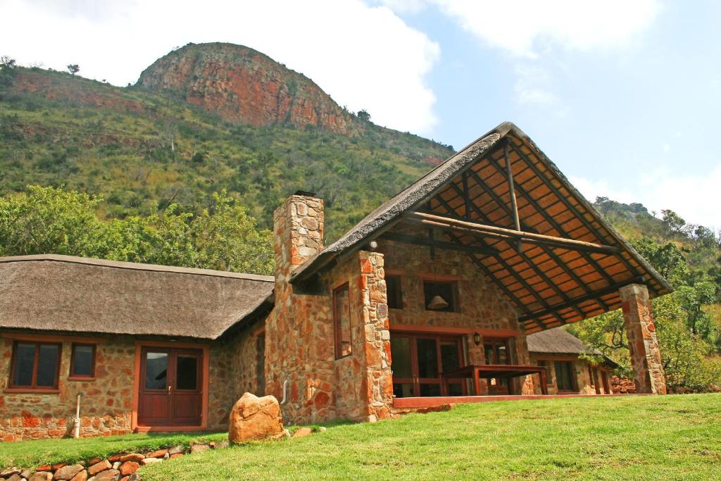 a stone house with a mountain in the background at Verlorenkloof in Dullstroom