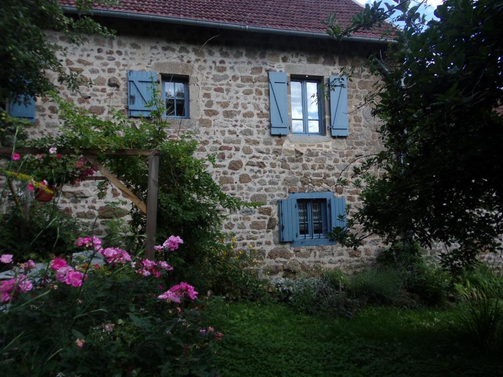 una vecchia casa in pietra con finestre blu e fiori di Petite Ferme d'Autrefois a Saint-Georges-Nigremont