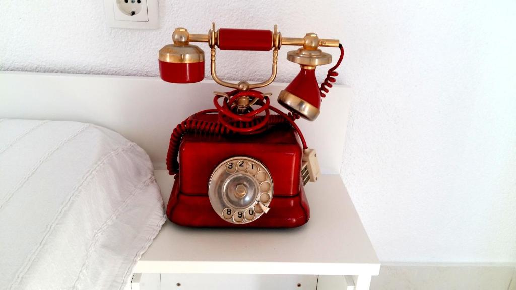 a red phone sitting on a table next to a bed at Apartments House of Art in Nin
