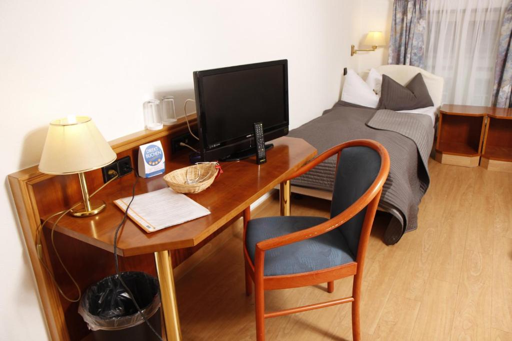 Schlafzimmer mit einem Schreibtisch, einem Computer und einem Bett in der Unterkunft Brocki's Hotel Stadt Hamburg in Parchim