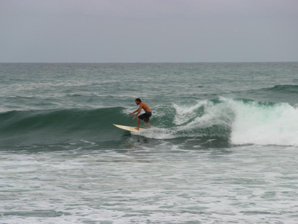 un hombre montando una ola en una tabla de surf en el océano en Marina Resort, en Mirissa