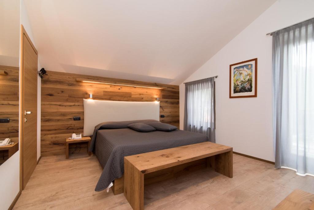 a bedroom with a bed and a wooden wall at Hotel Ferrovia in Calalzo