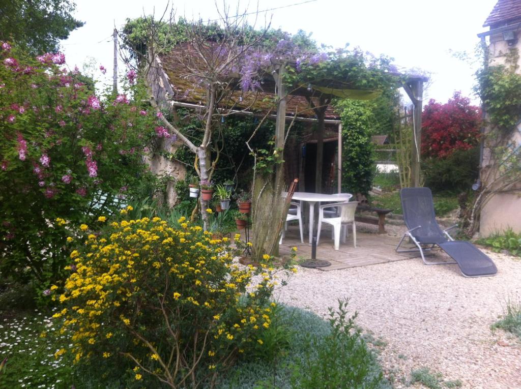 een tuin met een tafel, stoelen en bloemen bij Les 3 roses in Villeneuve-sur-Yonne