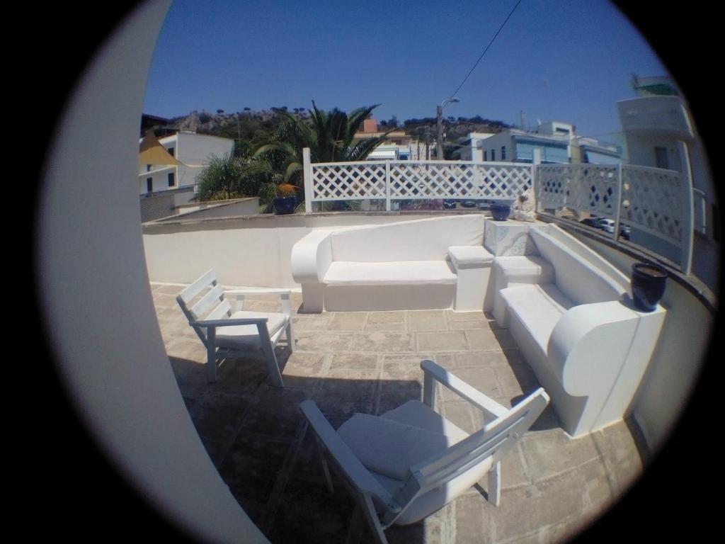 Lido Conchigliaにあるcasa con terrazzo in stile mediterraneoのバルコニー(白い家具、椅子付)が備わります。