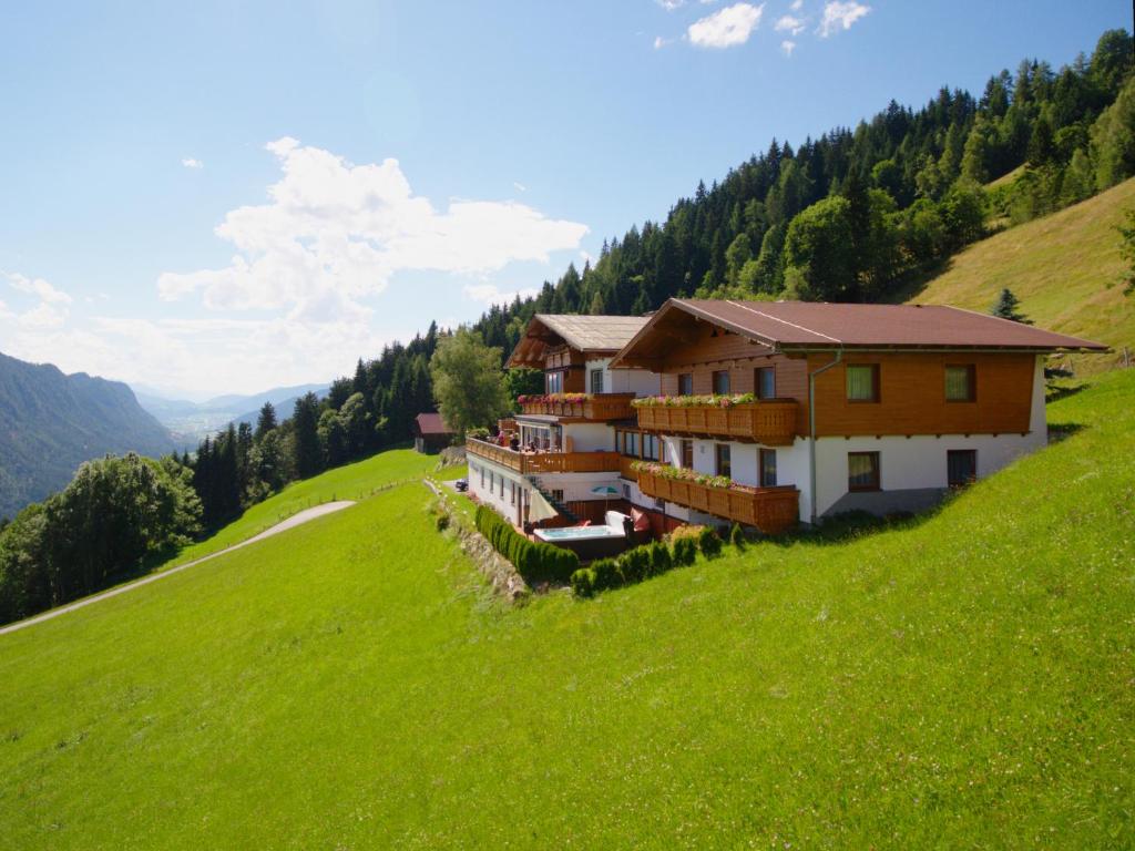 una casa en una colina con un campo verde en Pension Bergbauernhof Irxner, en Schladming