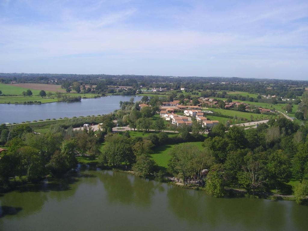 une vue aérienne sur un lac avec des maisons et des arbres dans l'établissement Pescalis Résidence Les Maisons du Lac, à Moncoutant