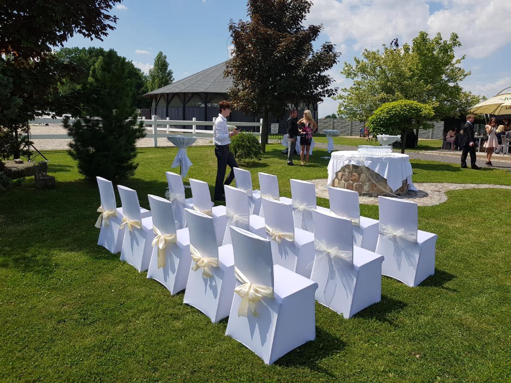 una fila de sillas blancas y una mesa en el césped en Master Horse Club - Svojetice, en Svojetice