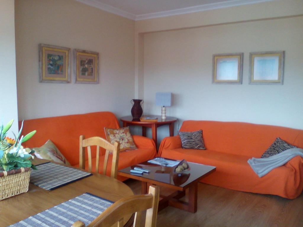 a living room with an orange couch and a table at Atico El Mirador in Pontevedra