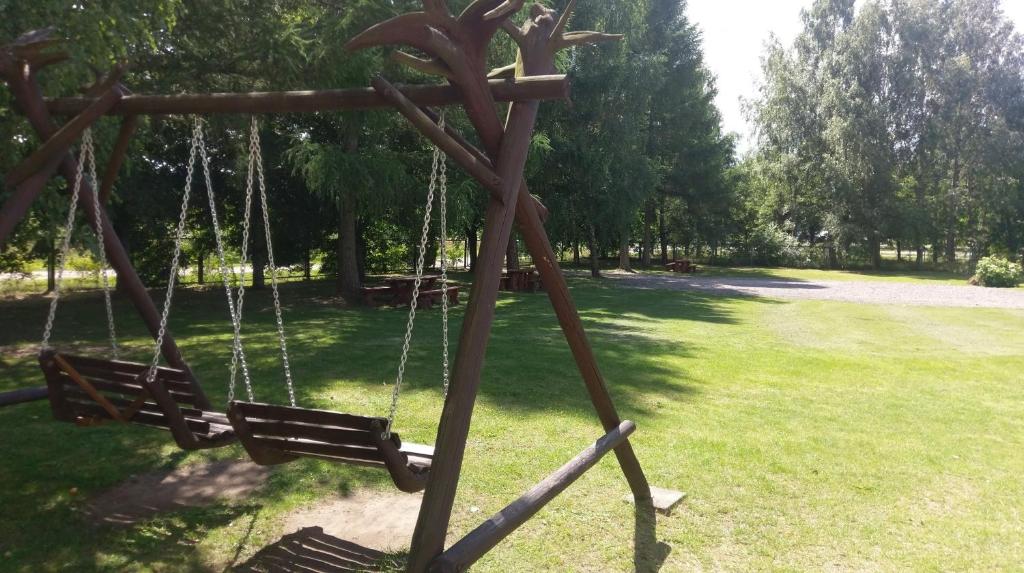 a wooden swing in a park with a grass field at Berzu aleja in Birštonas
