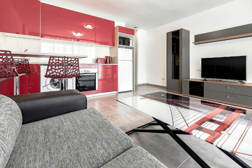 a living room with a couch and a tv and red cabinets at Apartmento Parque Royale I in Adeje