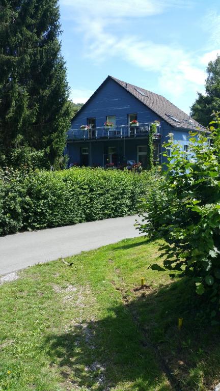 a blue house with a balcony and a yard at Ferienwohnung Eschenbeek in Wuppertal