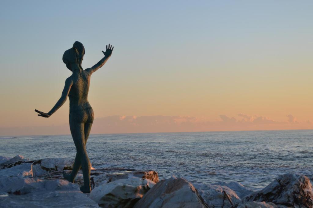 トッレ・デル・ラーゴ・プッチーニにあるA pochi passi dal mareの海辺の岩に立つ女像