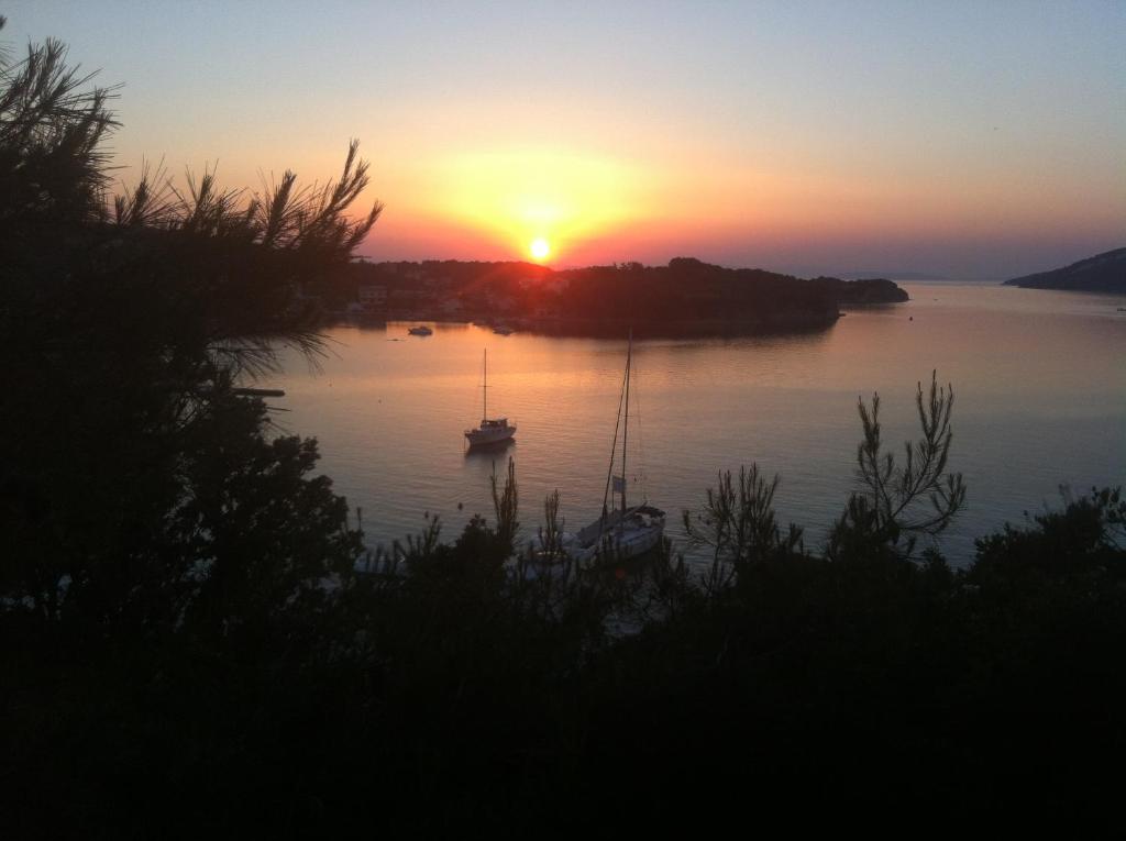 a sunset over a body of water with boats in it at Belveder Deluxe Suite and Rooms in Supetarska Draga