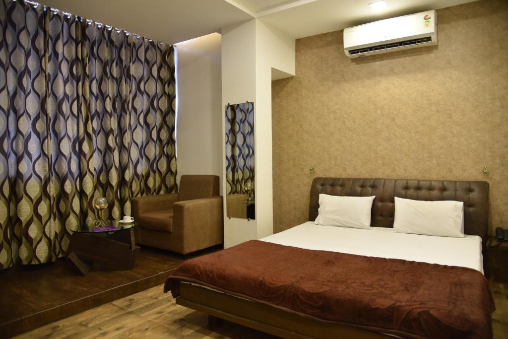 um quarto com uma cama e uma cadeira em Hotel Alankar em Aurangabad