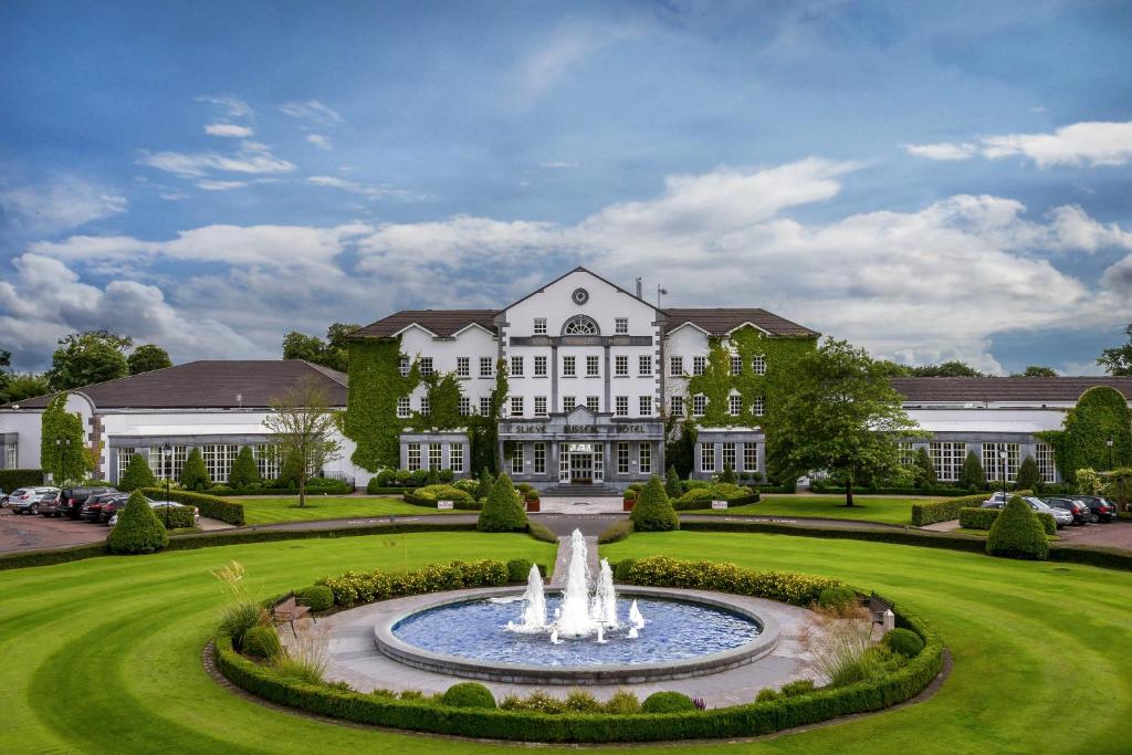 Une grande maison blanche avec une fontaine en face de celle-ci dans l'établissement Slieve Russell Hotel, à Ballyconnell