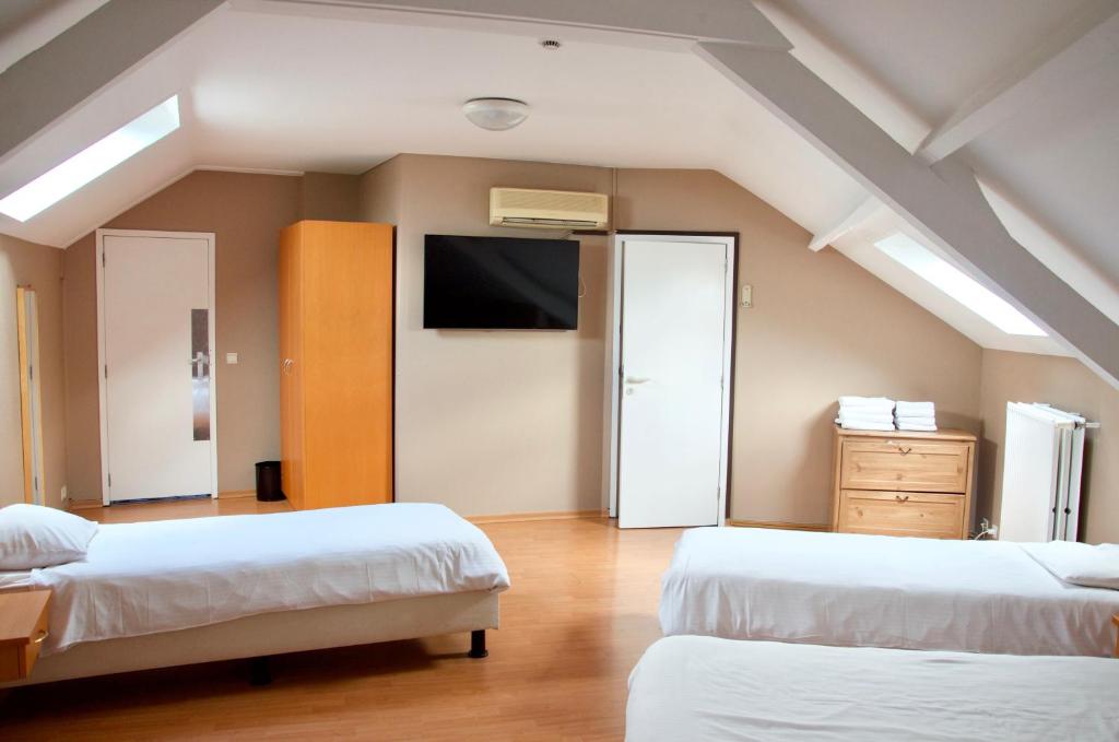 1 dormitorio con 2 camas y TV en la pared en Hotel Frederiksborg, en Bruselas