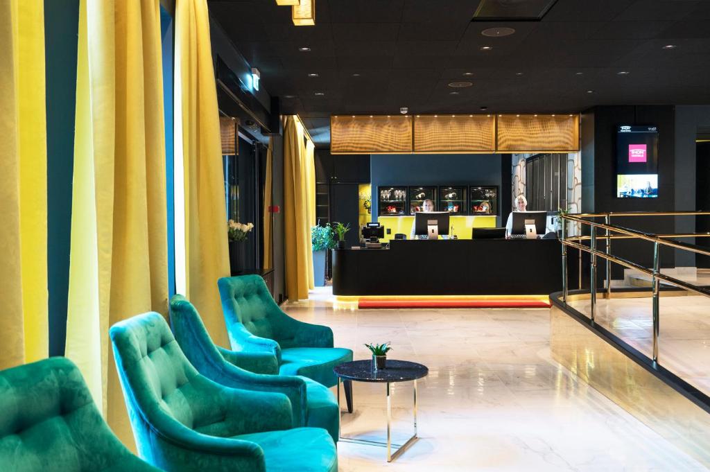 a lobby with green chairs and a table and a counter at Thon Hotel Orion in Bergen