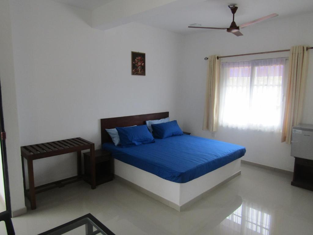 a bedroom with a bed with blue sheets and a window at Queens Park Apartments in Colombo