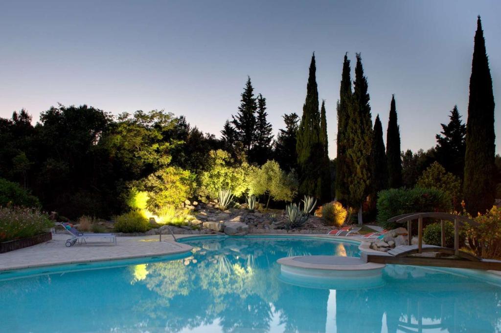 una gran piscina en un patio con árboles en La Villa Vicha, The Originals Relais, en Aubais