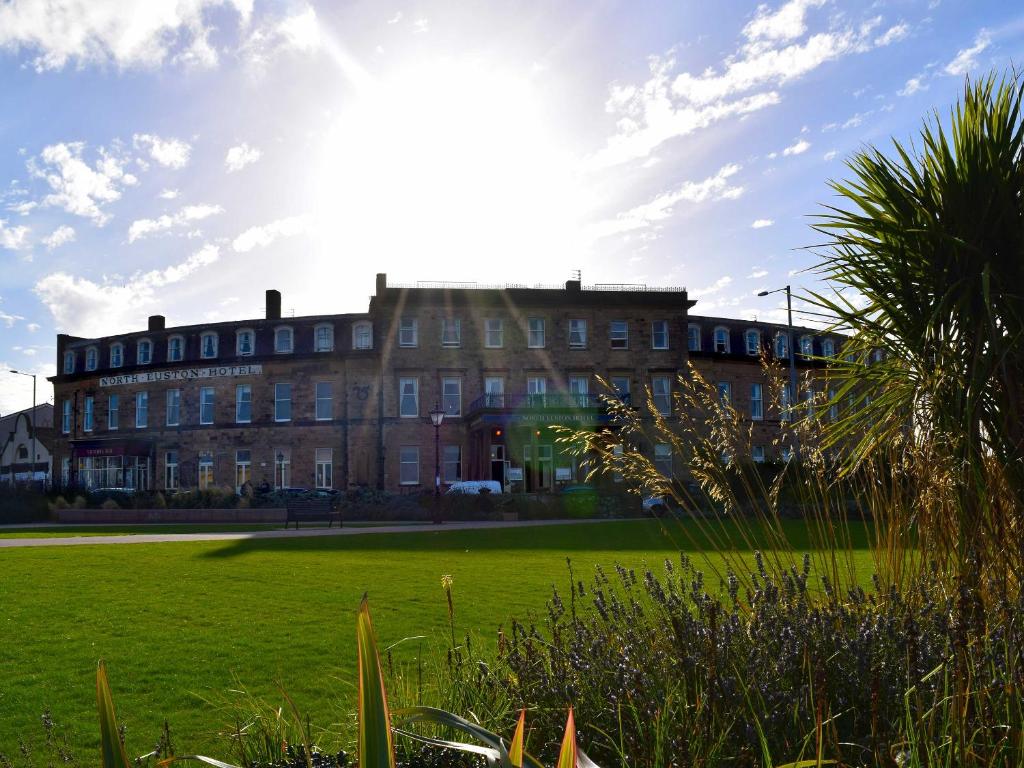 a large brick building with the sun in the sky at The North Euston Hotel in Fleetwood