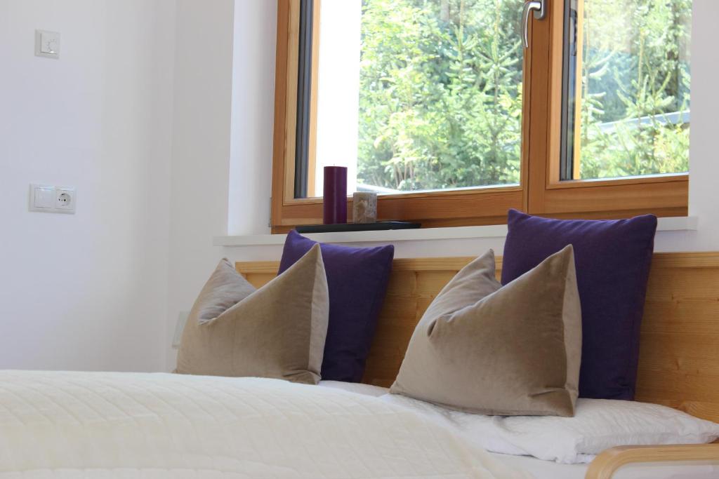 ein Schlafzimmer mit einem Bett mit blauen Kissen und einem Fenster in der Unterkunft Apartment Plan Corones in Bruneck
