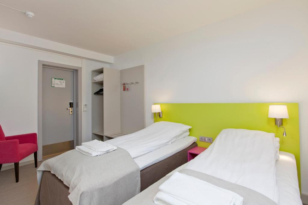 a hospital room with two beds and a red chair at MediInn Hotel Oslo in Oslo