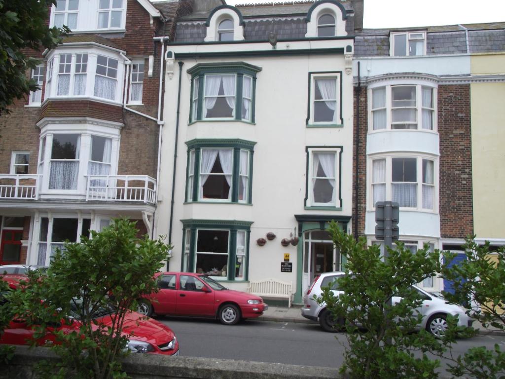 een wit huis met auto's ervoor geparkeerd bij beaufort guesthouse in Weymouth