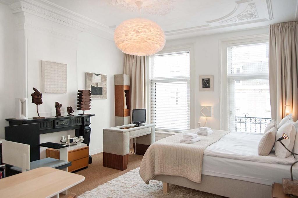 a white bedroom with a bed and a desk and a television at The Market Retreat in Amsterdam