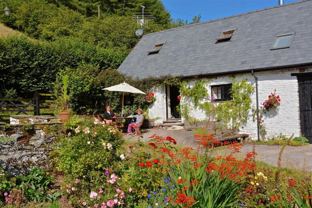 two people sitting at a table in front of a house at Barn Cottage in Brecon