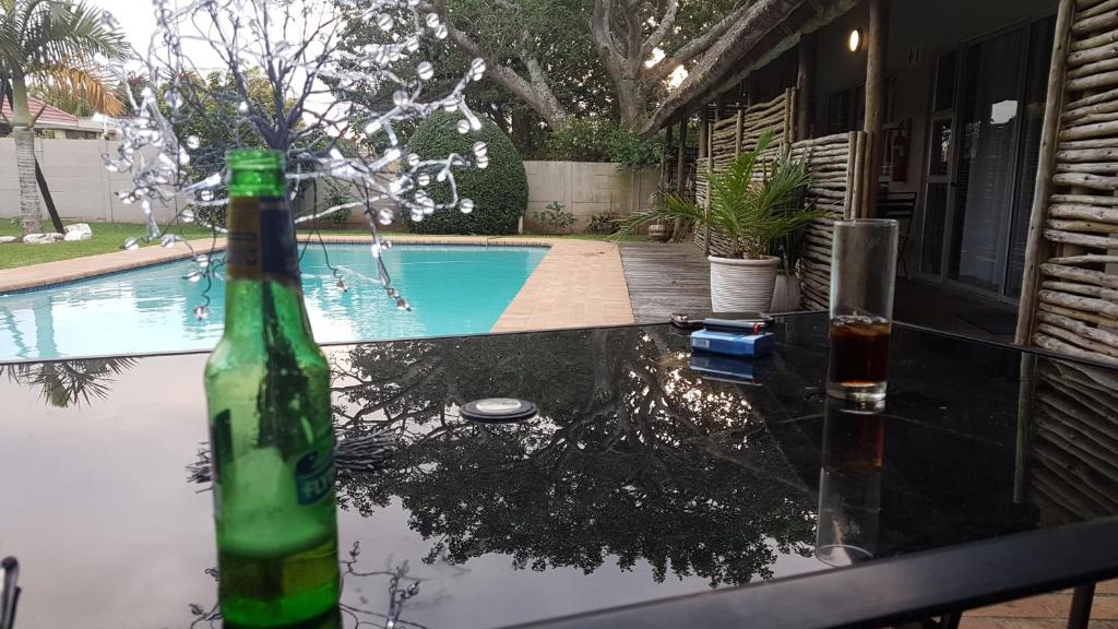 a bottle of wine sitting on a table next to a swimming pool at Riversway Guest House in East London