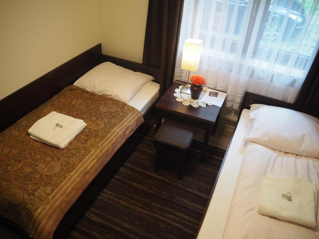 Habitación de hotel con 2 camas y una mesa pequeña. en Willa Zacisze - Apartament dwupoziomowy, en Kalwaria Zebrzydowska