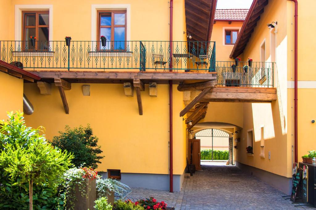 波傑布拉迪的住宿－Pension Viktorin，带阳台的黄色建筑和庭院