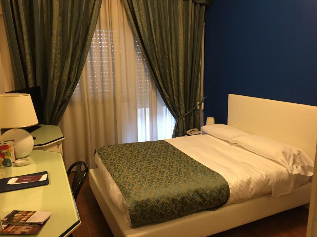 Grande Albergo Potenza في بوتنزا: غرفة نوم بسرير وطاولة ونافذة