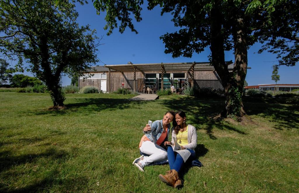 ロシュフォールにあるAuberge de jeunesse Rochefortの二人の女性がカメラを持って芝生に座っている