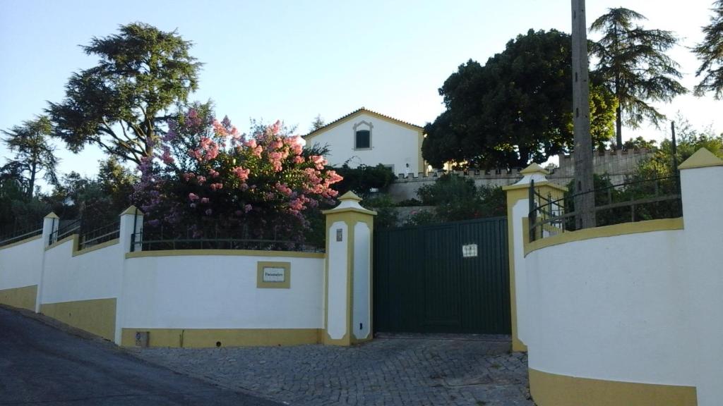 une clôture blanche avec un portail avec une brousse fleurie dans l'établissement Vila Maria, à Castelo de Vide