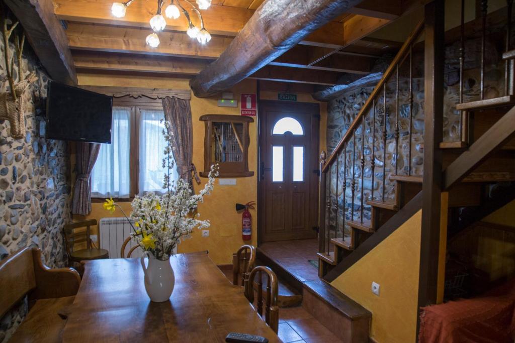 un comedor con una mesa con un jarrón de flores. en La Casina de Terobe, en Cacabelos